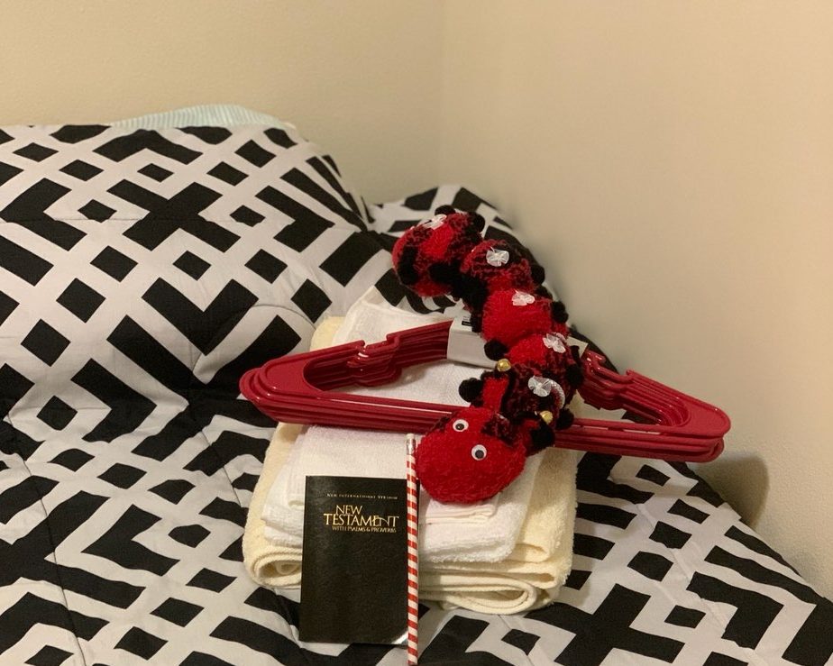 A made bed with towels and a New Testament ready for a new resident